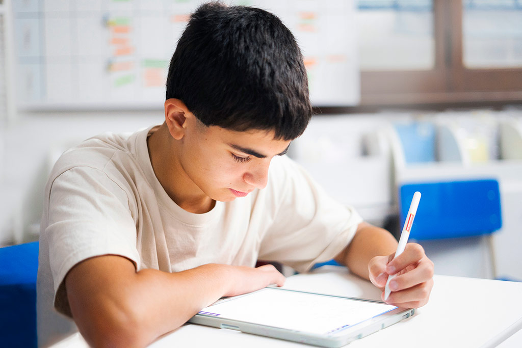 Estudiante en Kumon practicando escritura y lectura en una tableta, enfocada en su aprendizaje.
