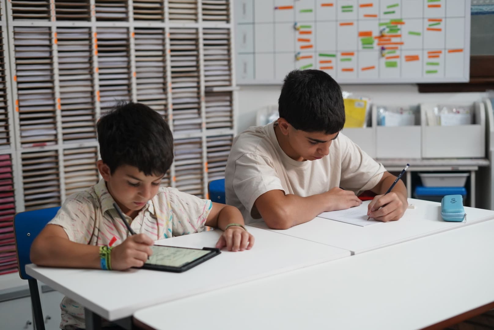Alumnos haciendo la tarea en el material didáctico, la tablet y el cuadernillo-Argentina
